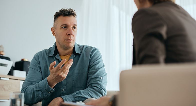 A man and woman engage in discussion in an office, representing the effects of drug addiction on family relationships.