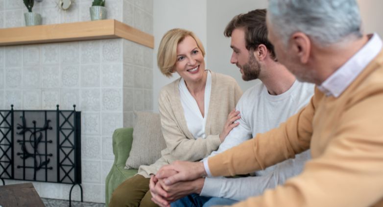 A family sit on a couch, representing trust and support in the context of drug addiction's impact on family dynamics.