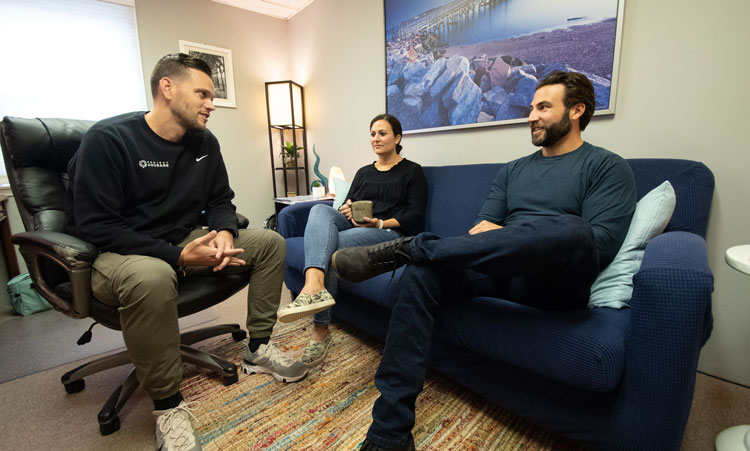 Three individuals comfortably sitting on a couch in an office, highlighting Addiction Recovery Services in Clinton