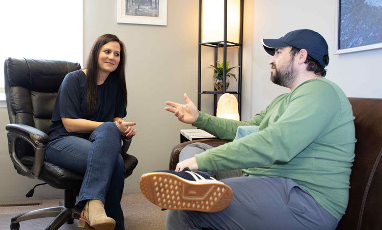 In an office, a man and woman discuss therapy options at a Drug Rehab Center in Westport, emphasizing intensive outpatient care.