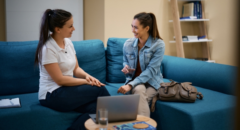 Two women seated on a couch, sharing insights on recovery options for a family member dealing with drug addiction.