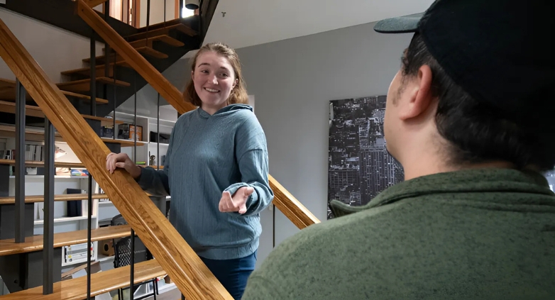 A woman and a man pose in front of a staircase, representing the journey of helping a drug addict family member with compassion.