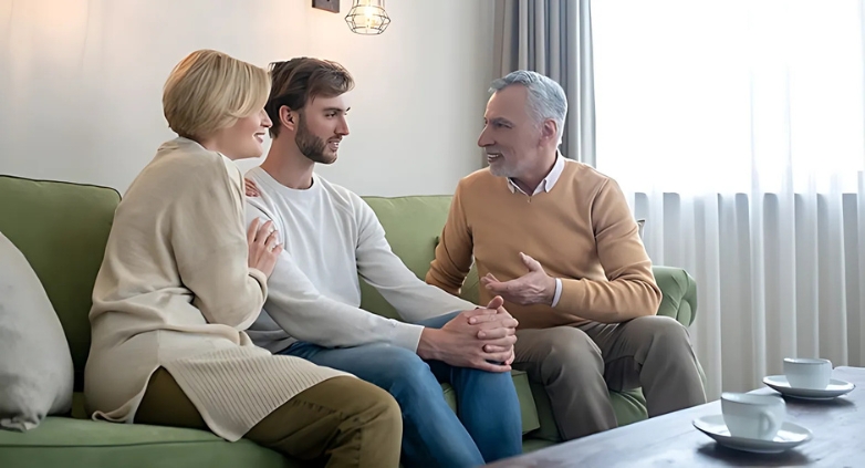 A man and woman converse on a couch with another man, showcasing the support for a family member in recovery from addiction.