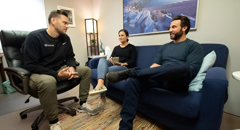 Three people on a couch in an office setting, focused on understanding and addressing addiction within the family context.