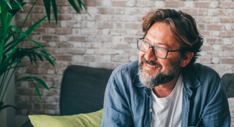 A man with glasses and a beard is seated on a couch, emphasizing the significance of early awareness of drinking problems.