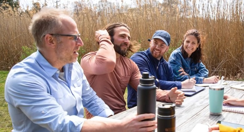 A group of people at a picnic table, collaborating on strategies to help someone with addiction through ongoing support.