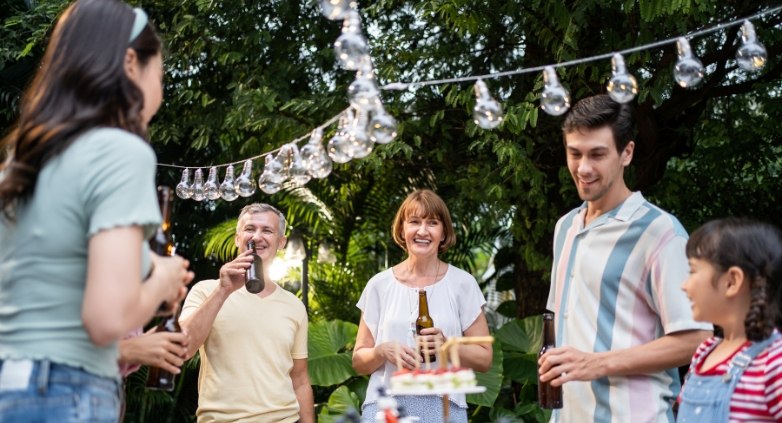 A cheerful gathering of people in a backyard, enjoying food and drinks at a vibrant party atmosphere.