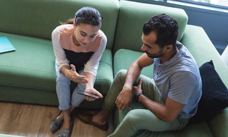 A man and woman seated on a couch look at a cell phone, seeking information on opioid addiction treatment in Chester, CT.