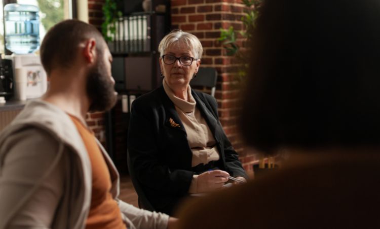 A woman talks with two individuals in a coffee shop, focusing on intensive outpatient therapy for opioid addiction in Essex, CT.