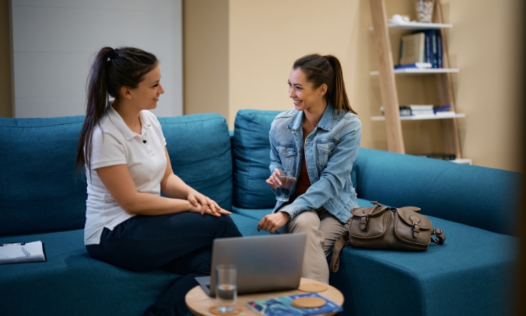 Two women sitting on a couch engaged in conversation, representing family counseling for addiction recovery in CT.