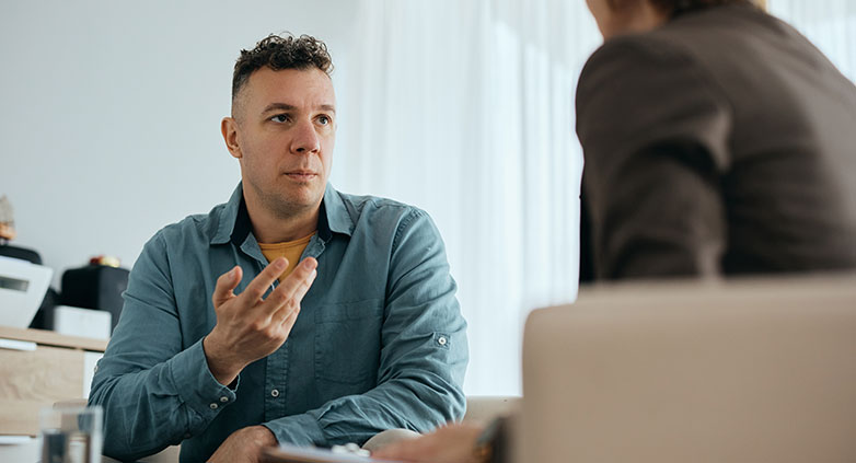 People sitting together at a table, actively participating in a drug addiction process group discussion.