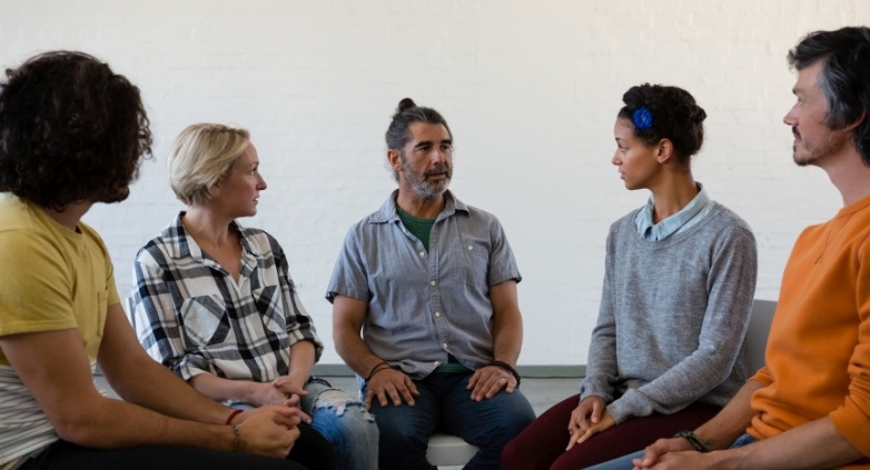 A group of individuals seated in a circle, engaged in discussion during a drug addiction therapy session.