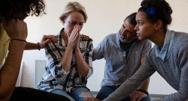 In a relapse prevention group, individuals sit, with one member expressing emotions through tears.