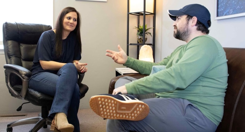 A man and woman engaged in conversation in an office setting, discussing topics related to seeking help for alcoholism.
