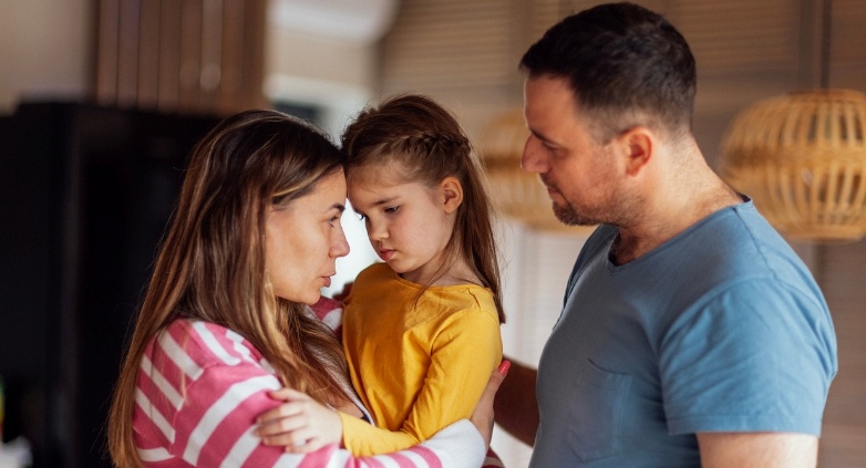 A man and woman support a little girl, representing the challenges children face in families affected by addiction.