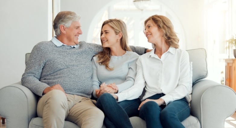 A family sits on a couch, conveying compassion and togetherness as they navigate challenges related to an alcoholic daughter.