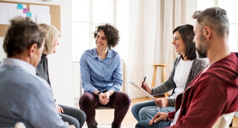 A group of people sitting in a circle, engaged in a supportive discussion about helping a person with alcoholic use disorder.