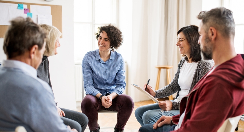 A group of people sitting in a circle, engaged in a supportive discussion about helping a person with alcoholic use disorder.