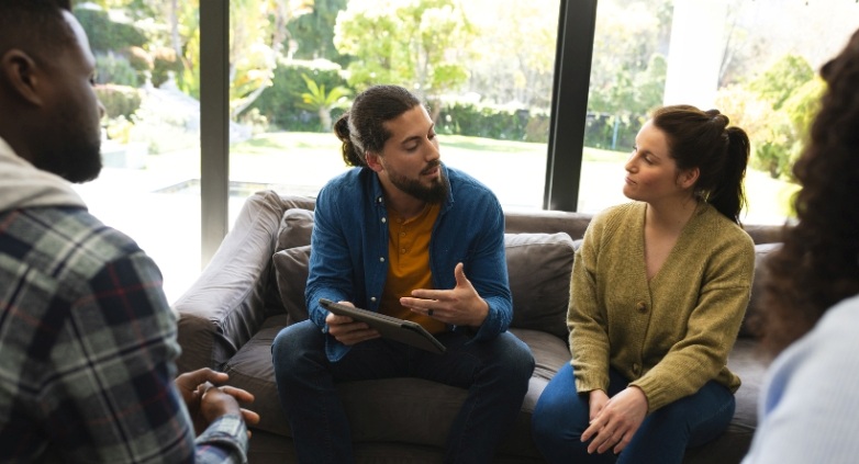 A man and woman converse with therapists on a couch about seeking help for marriage challenges involving alcoholism.