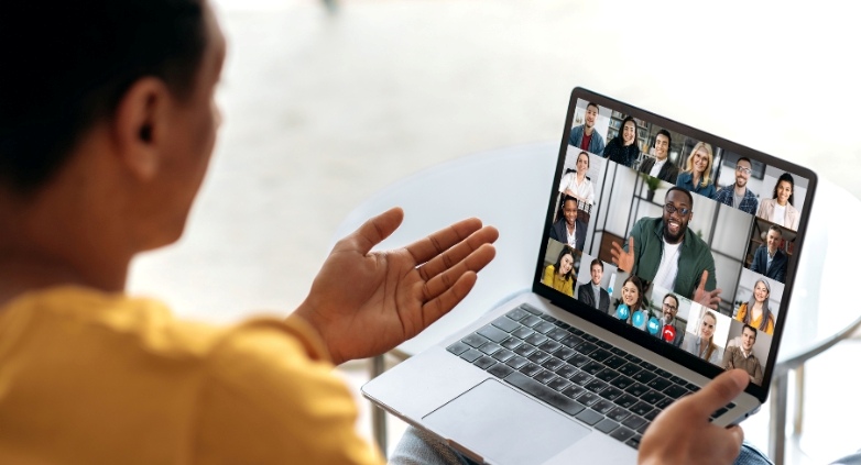 A person at a table with a laptop, engaging with a group displayed on the screen for Families in Recovery services.