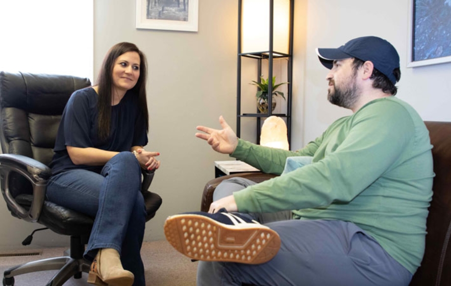 A professional office scene featuring a man and woman talking, focused on high-end drug rehab options in Connecticut.