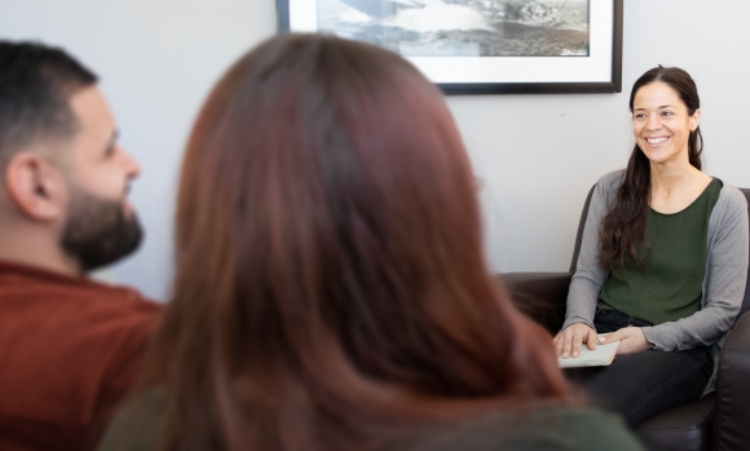 A woman sitting with two men and another woman, focused on high-end drug rehabilitation discussions in Connecticut.
