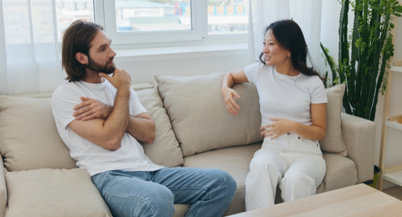 A man and woman talk on a couch, focusing on the importance of boundaries in addiction recovery for those they care about.