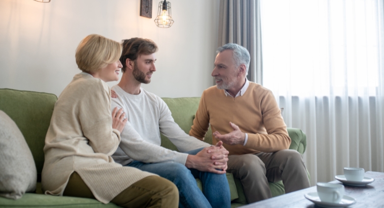 A son and parents talks on a couch, showcasing family roles in helping someone maintain sobriety.