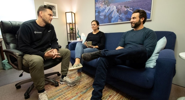Three people discussing on a couch in an office, focusing on strategies to support ongoing sobriety treatment.