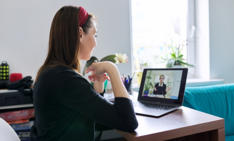 A woman engaged in a video call at her desk, participating in one-on-one virtual counseling for addiction treatment.