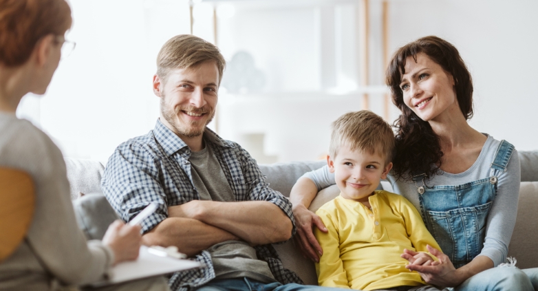 A family sitting on a couch with a child, representing in-home family therapy for addiction treatment.