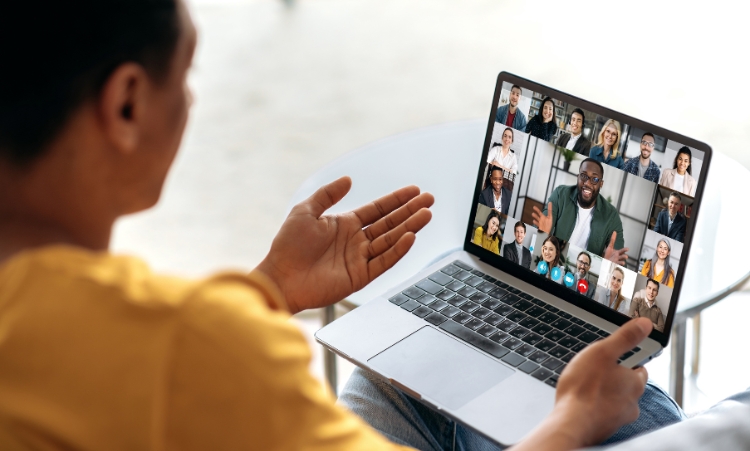 A person in front of a laptop, involved in a virtual group therapy session for alcohol abuse with a group of people visible.