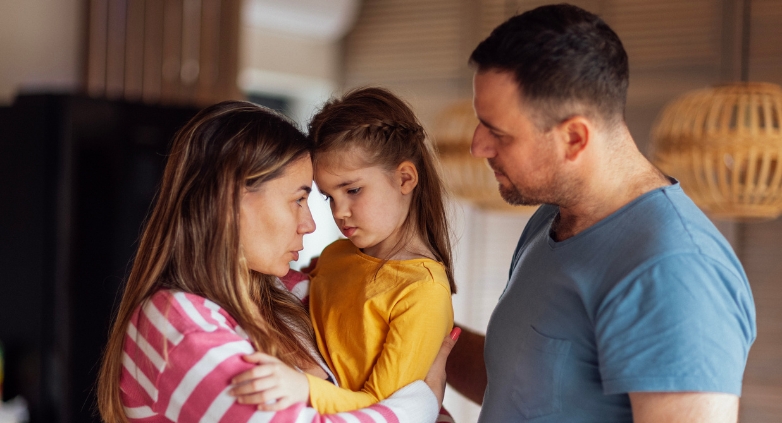 A man and woman supportively hold a little girl, illustrating the emotional impact of having an alcoholic father.