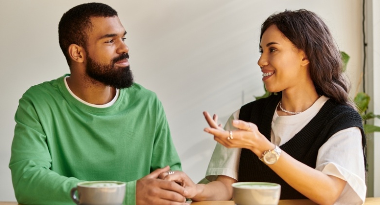 A man and woman at a table with coffee cups, focused on a conversation about navigating codependency and supporting an alcoholic father.