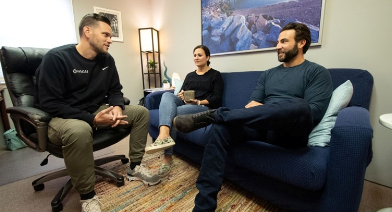 Three people on a couch in an office, talking about seeking professional help for drinking issues during the holiday season.