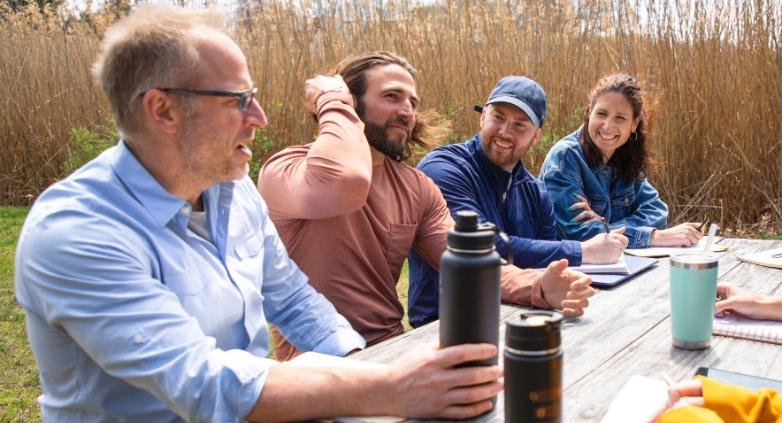 A group of people gathered at a picnic table, discussing the impact of holiday drinking habits.