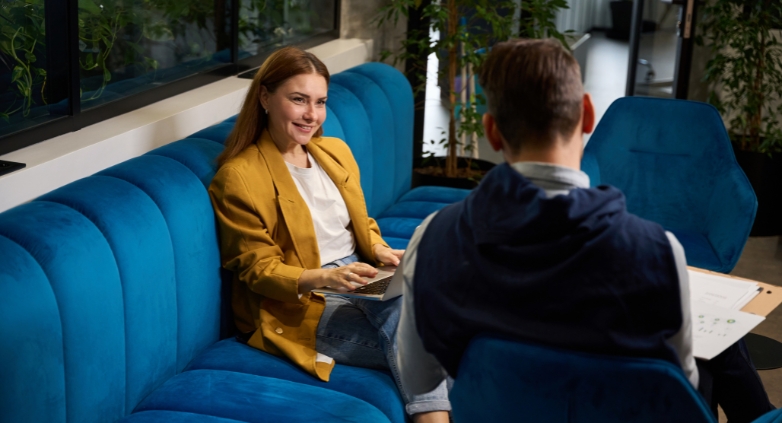 A man and woman are on a couch in an office, collaborating on a plan to maintain sobriety during the holiday season.