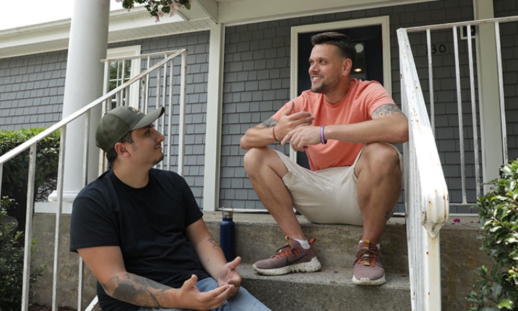 Two men seated on house steps, engaged in conversation about in-home recovery services for alcohol abuse in Connecticut.