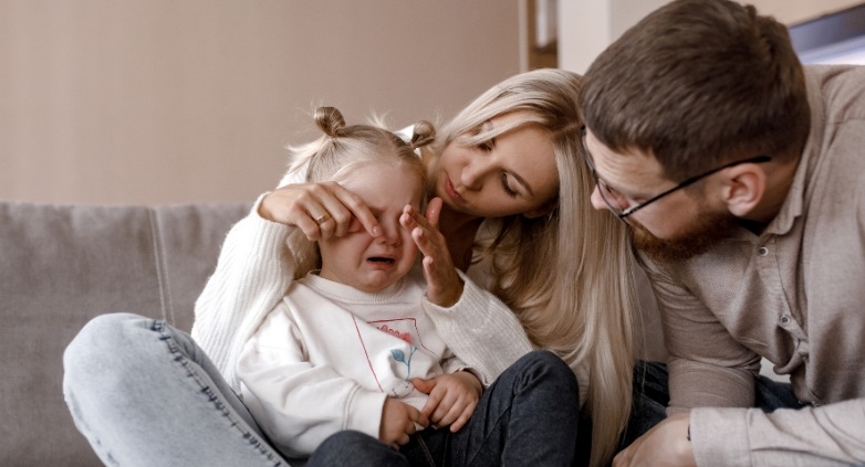 A man and woman are seated on a couch with a child, illustrating family interactions in the context of alcohol-related challenges.