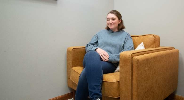 A woman seated in a chair within a room, embodying the themes of connection and the practice of "Just Being."