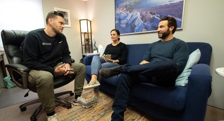 Three people on a couch in an office, talking about seeking professional help for drinking issues during the holiday season.