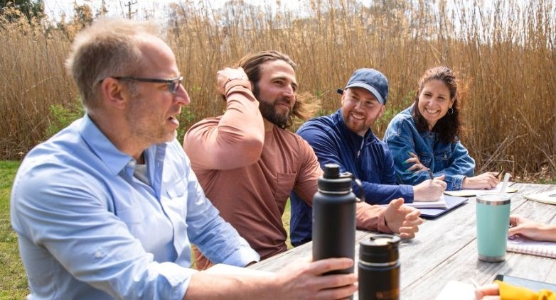 A group of people gathered around a picnic table, discussing the effects of drug addiction on family members.