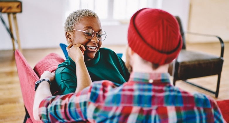 A man and woman are seated on a couch, focusing on how to support an alcoholic husband through treatment options.