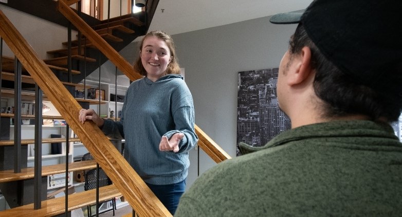 A woman and a man stand on the house stairs, contemplating strategies for helping a family member struggling with addiction.