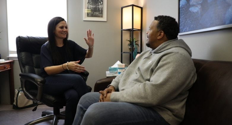 A man and woman talking in an office, focusing on how to recognize drinking issues and the clinical gold standard.