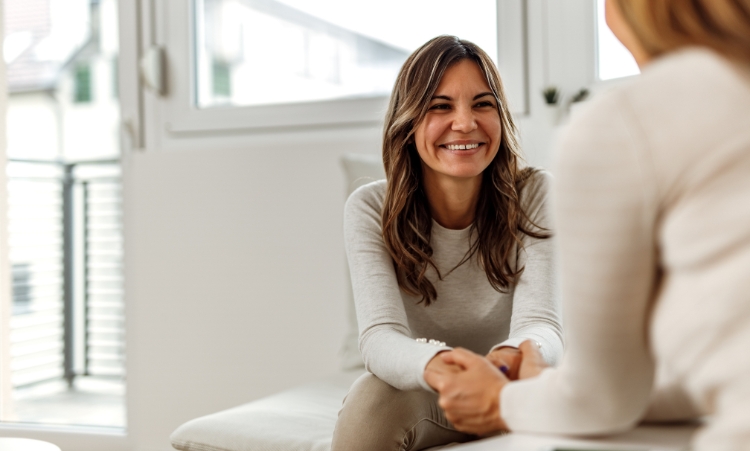 Two women converse in a living room, focusing on marijuana addiction treatment and in-home recovery services.