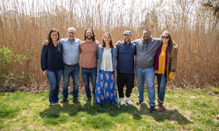 A group of people stands together in front of tall reeds, representing community support for methamphetamine addiction treatment.