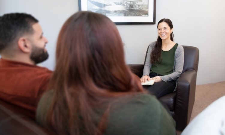 A woman sitting with two men and another woman, focused on discussions about in-home recovery for methamphetamine addiction.