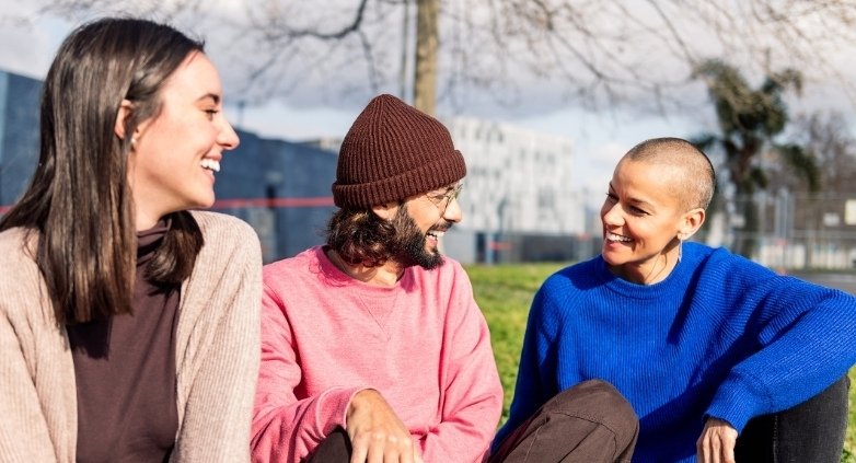 Three young friends on the grass, sharing thoughts on mental rehearsal for staying sober during the holidays.