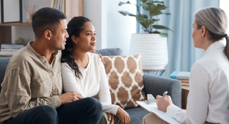 A therapist listens as a couple discusses their challenges on a couch, focusing on family resources for addiction support.